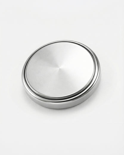 Round metallic object with a brushed finish on a plain white background.