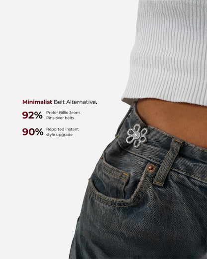 Close-up of a waist with a flower pin on denim jeans and a ribbed white top.