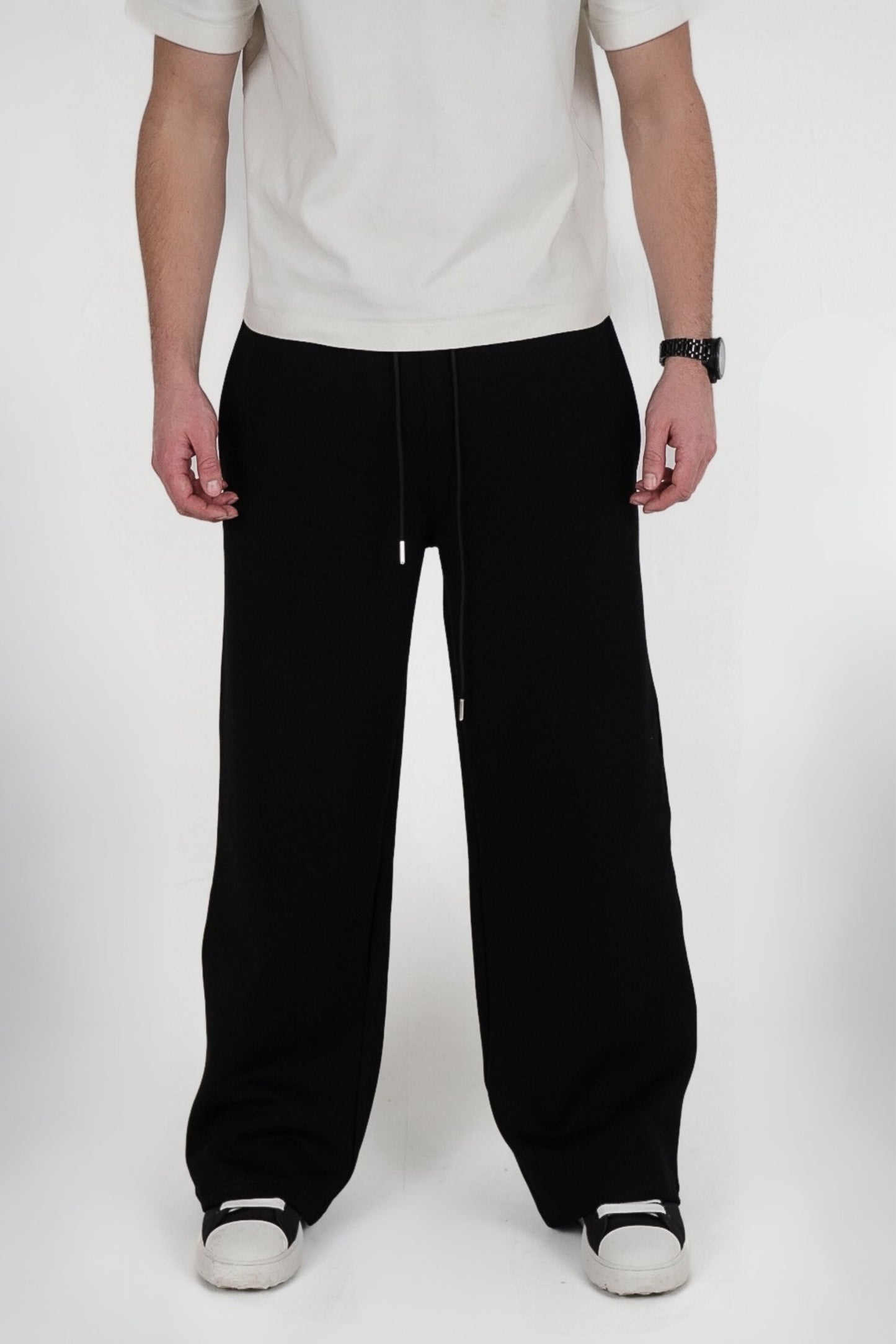Person wearing black pants and a white shirt on a white background