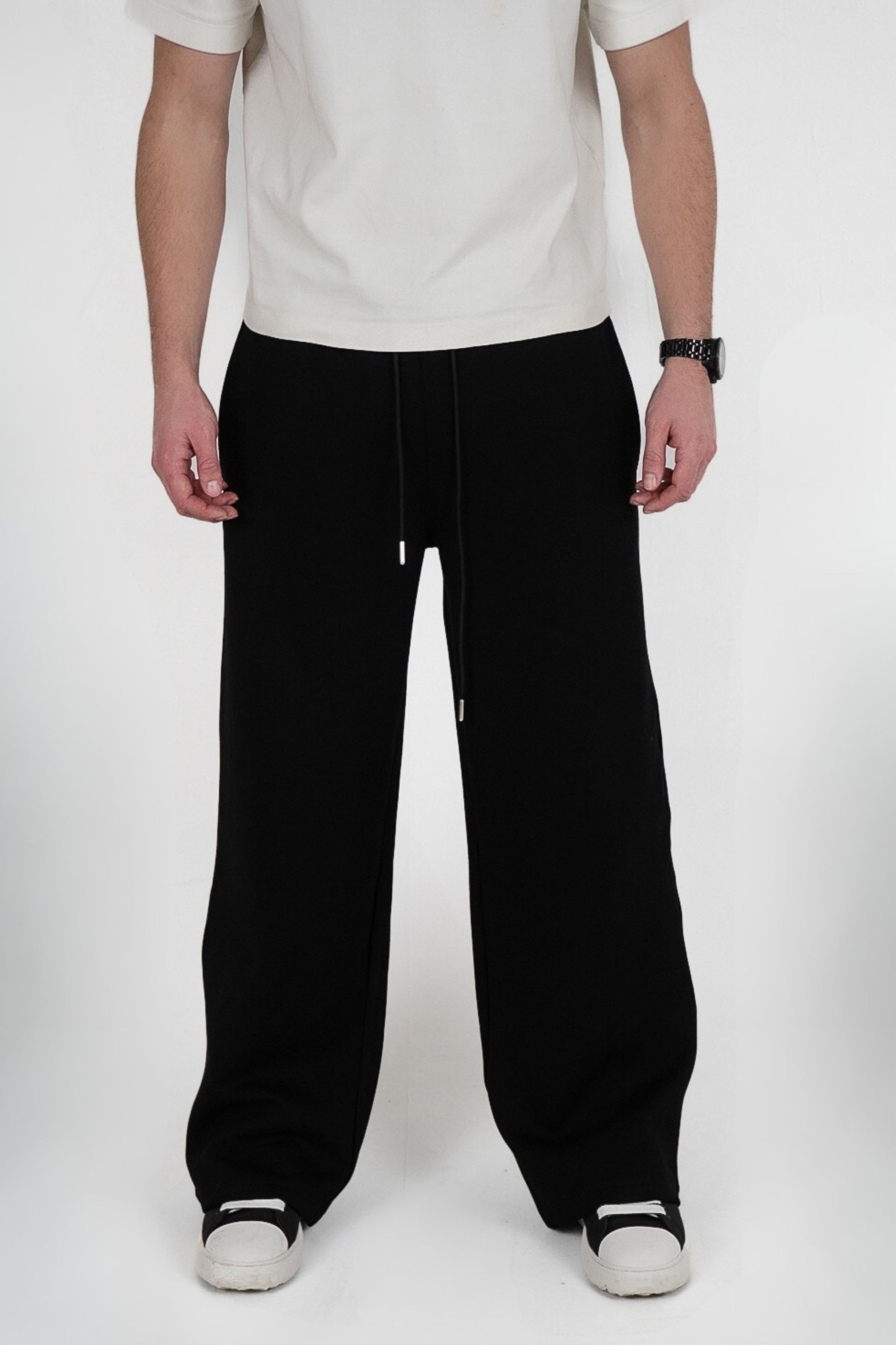 Person wearing black pants and a white shirt on a white background