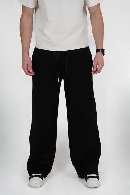 Person wearing black pants and a white shirt on a white background