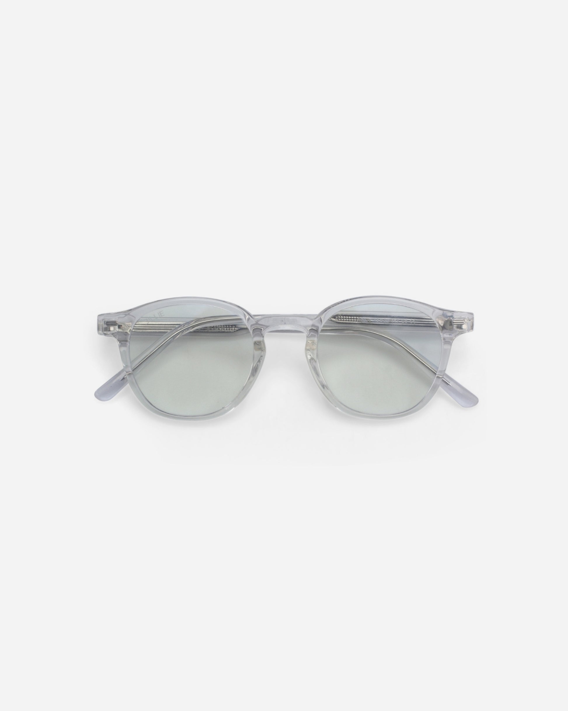 Clear framed sunglasses with light green lenses on a plain background