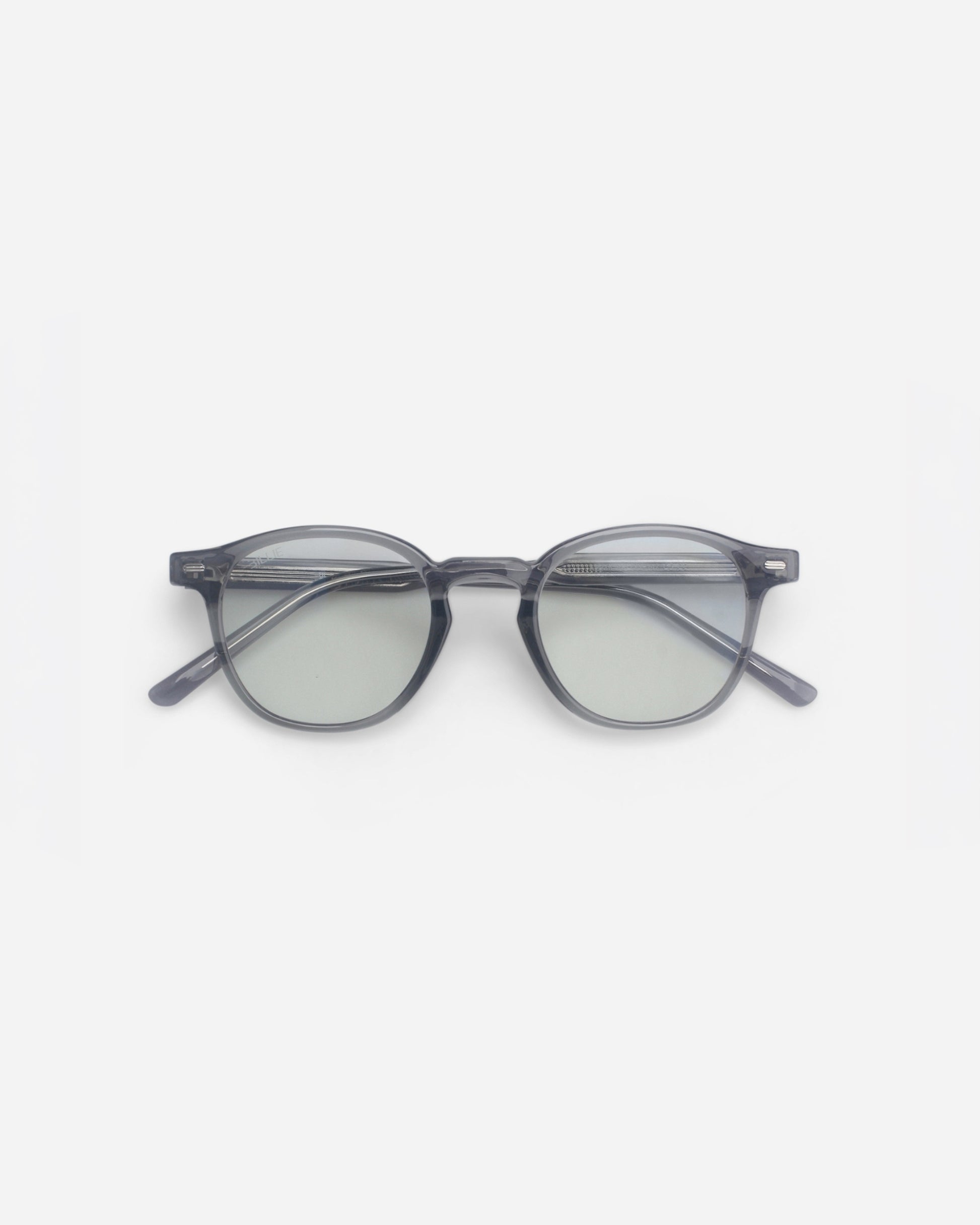 Round glasses with a transparent gray frame and light green lenses on a plain background.
