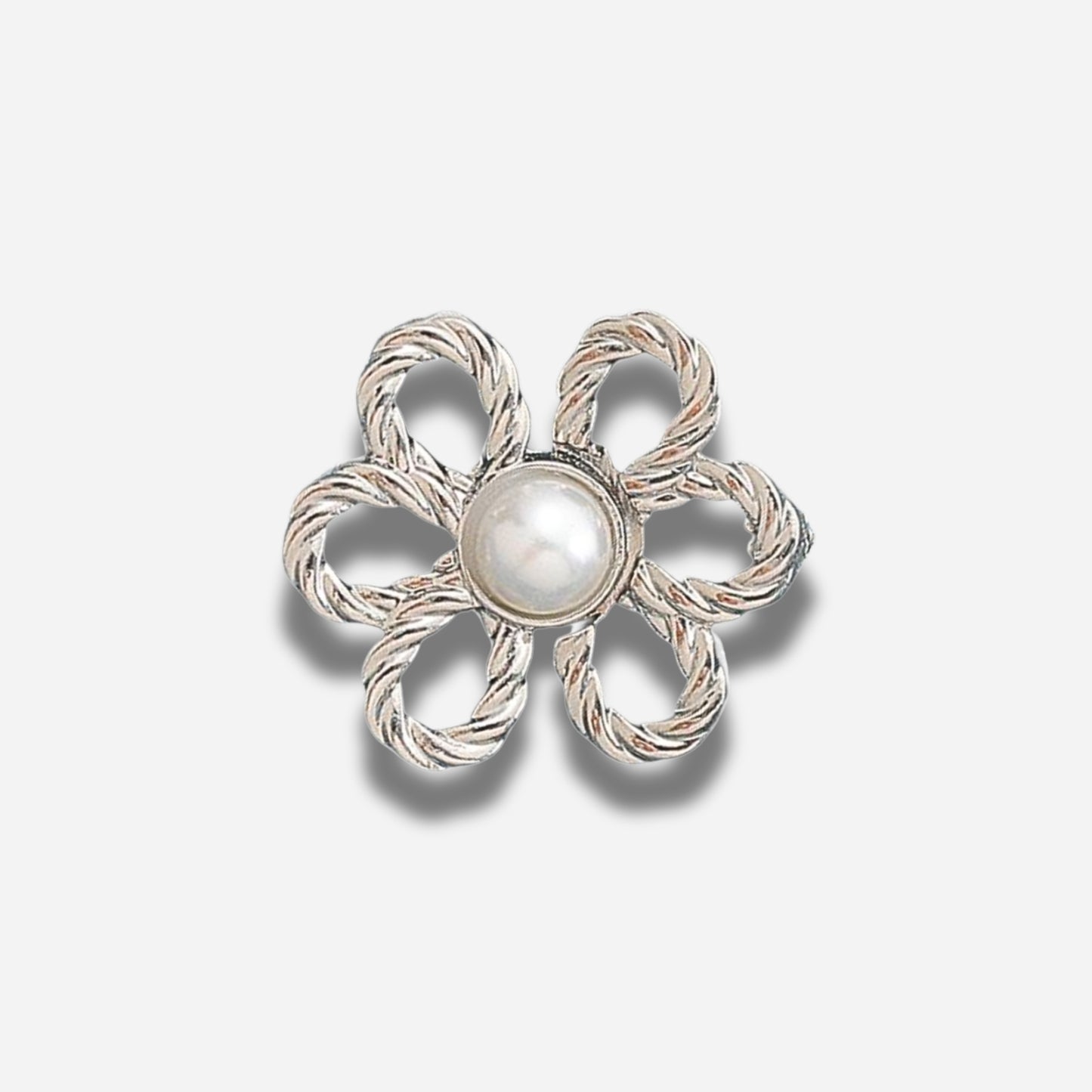 Zilveren bloemvormige broche met een centrale parel op een lichtgrijze achtergrond