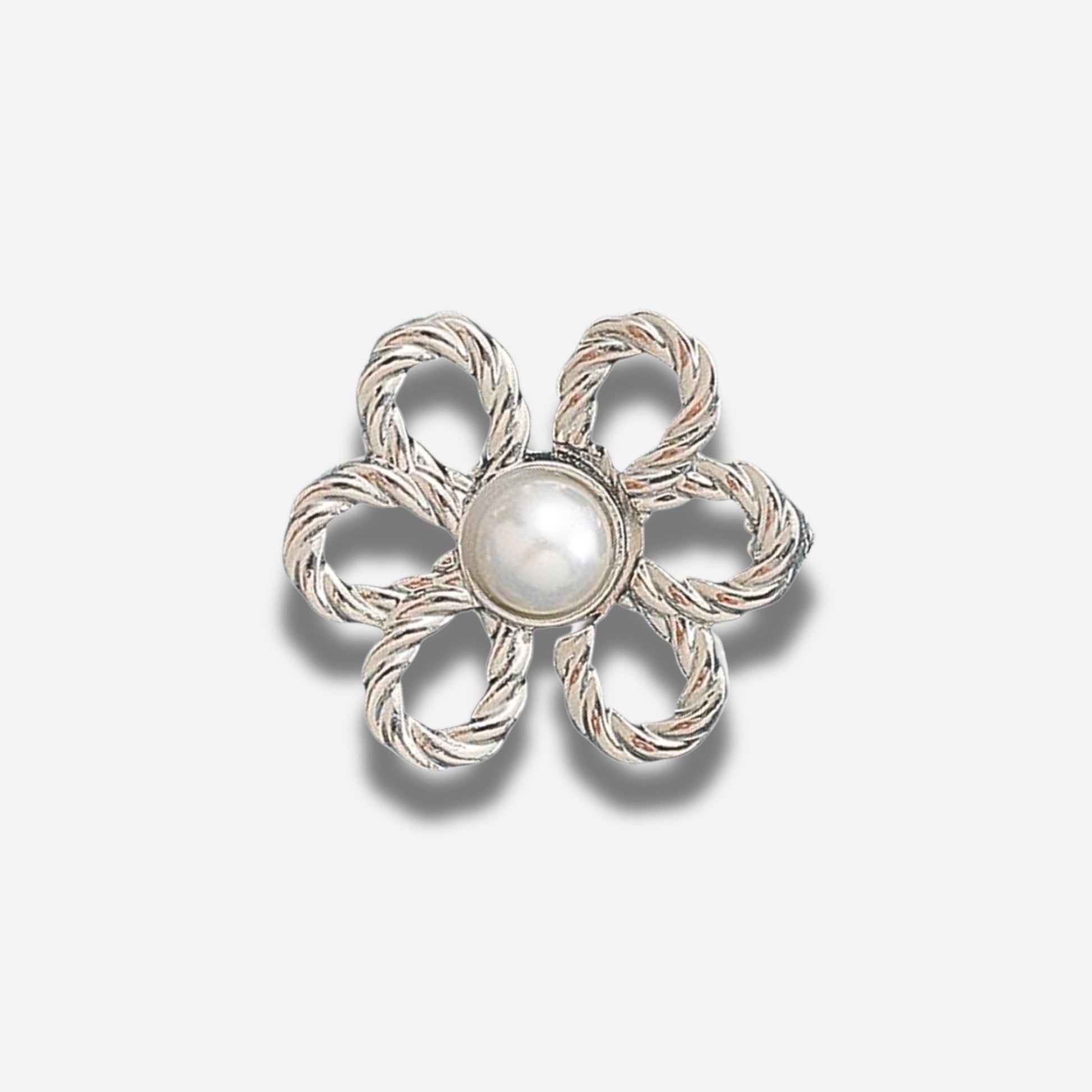 Zilveren bloemvormige broche met een centrale parel op een lichtgrijze achtergrond