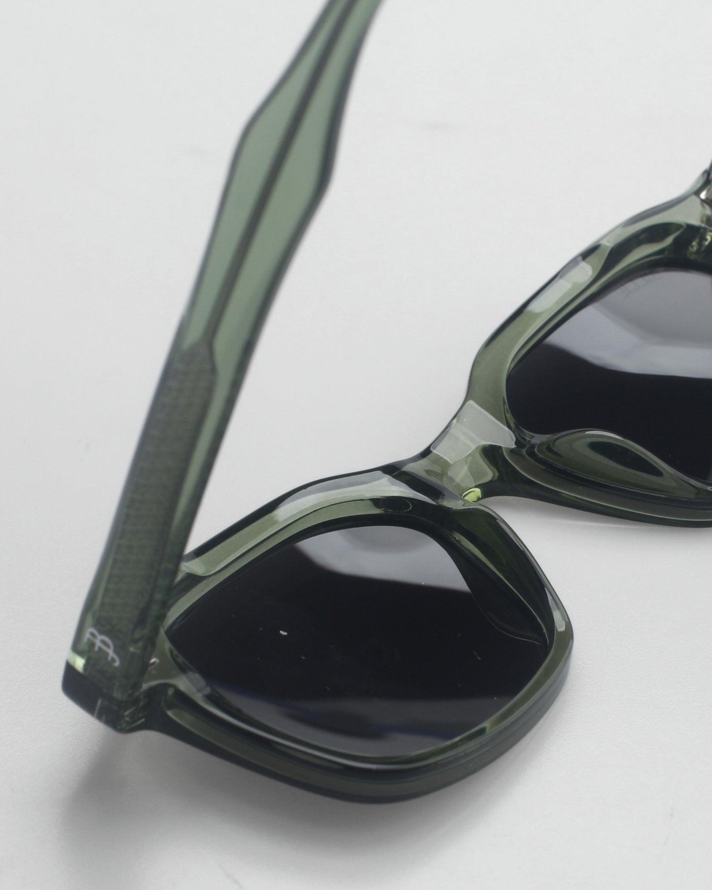 Close-up of green sunglasses with dark lenses on a plain background.
