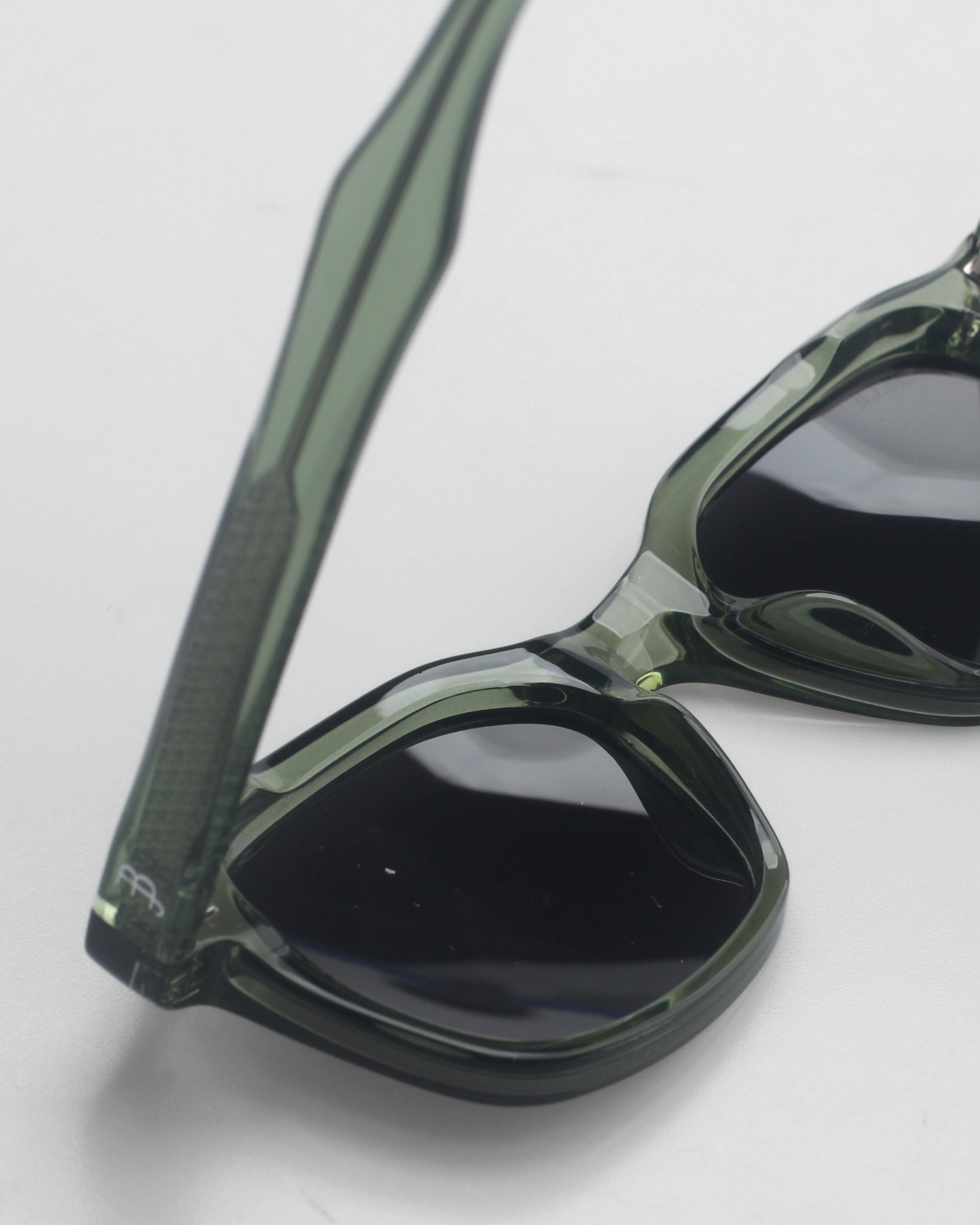 Close-up of green sunglasses with dark lenses on a plain background.
