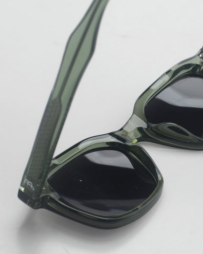Close-up of green sunglasses with dark lenses on a plain background.