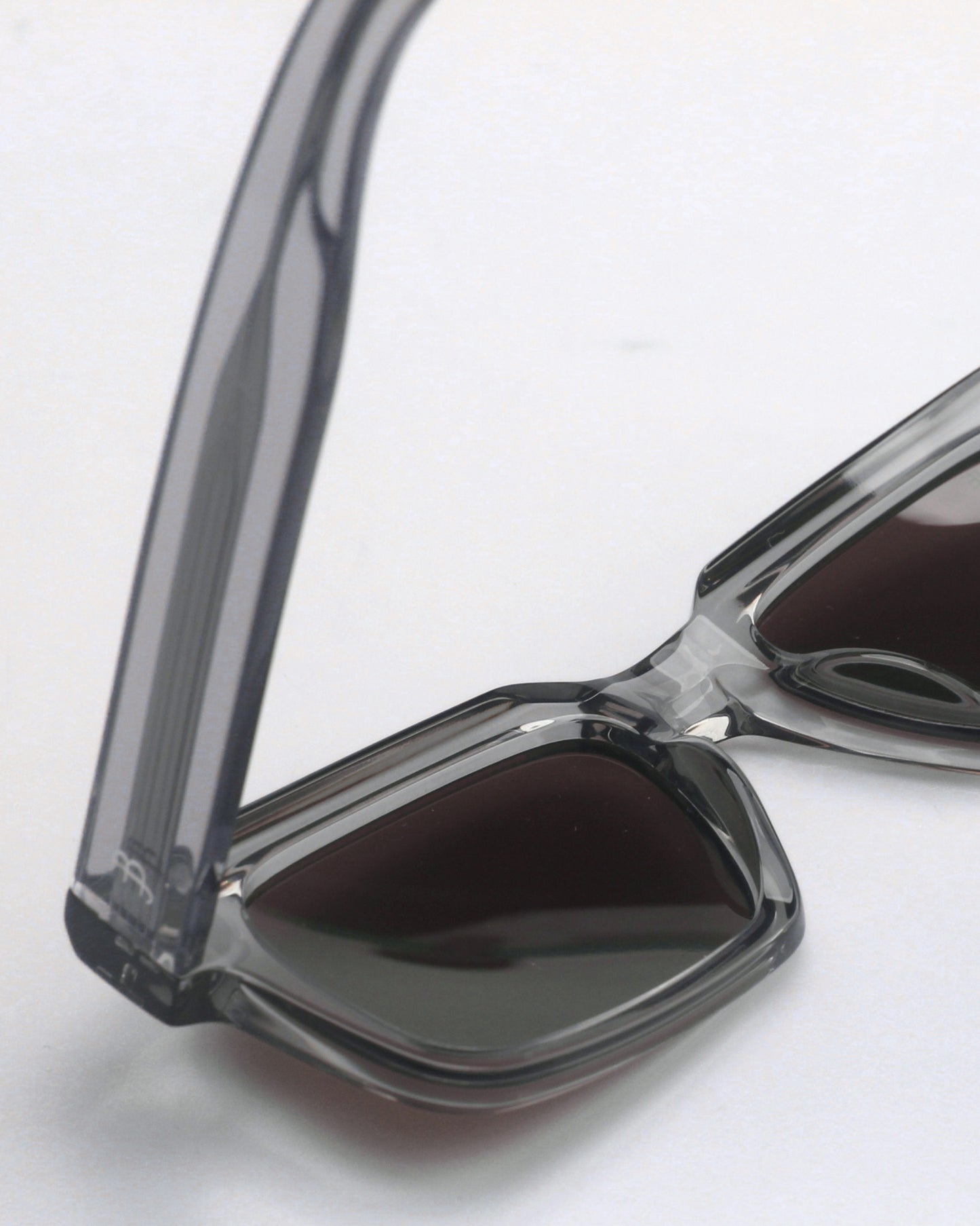 Close-up of gray sunglasses with dark lenses on a plain background.