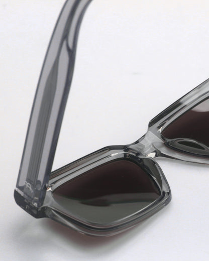 Close-up of gray sunglasses with dark lenses on a plain background.