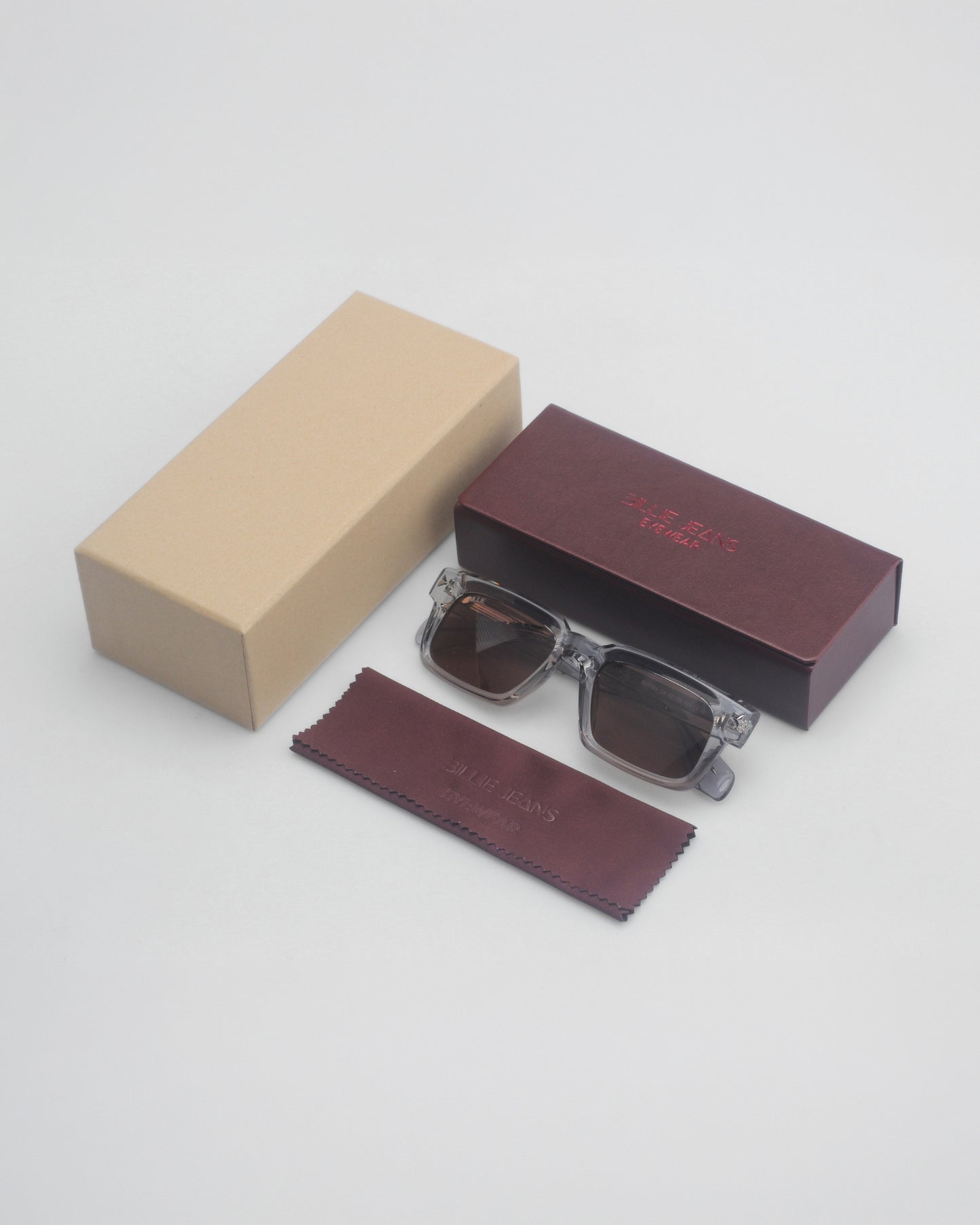 Sunglasses on a plain background with a brown box and a cleaning cloth.