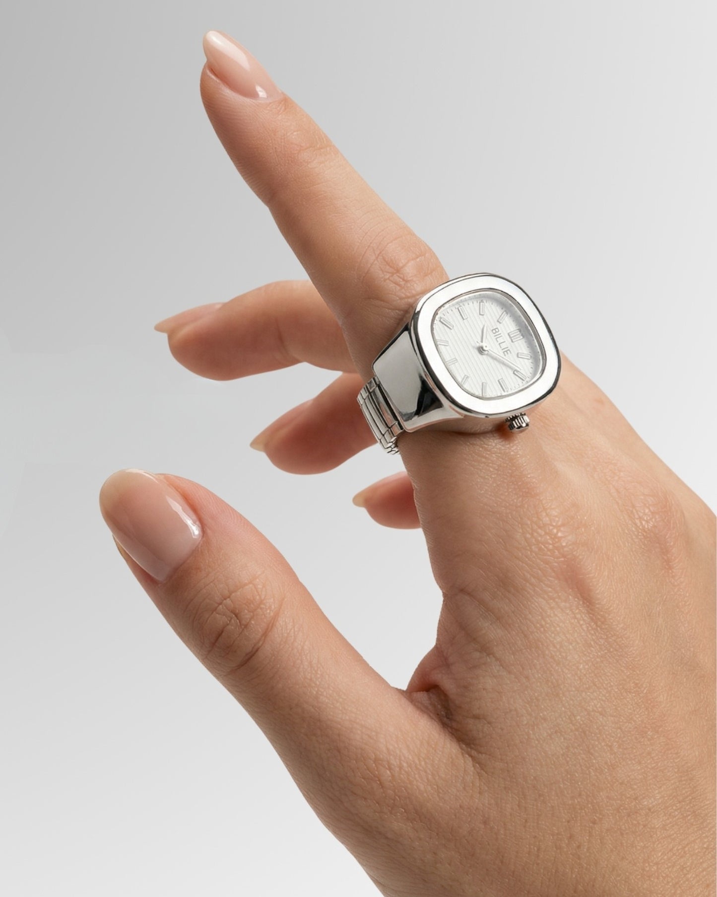 Hand with a silver watch, fingers slightly curled, on a gradient background.