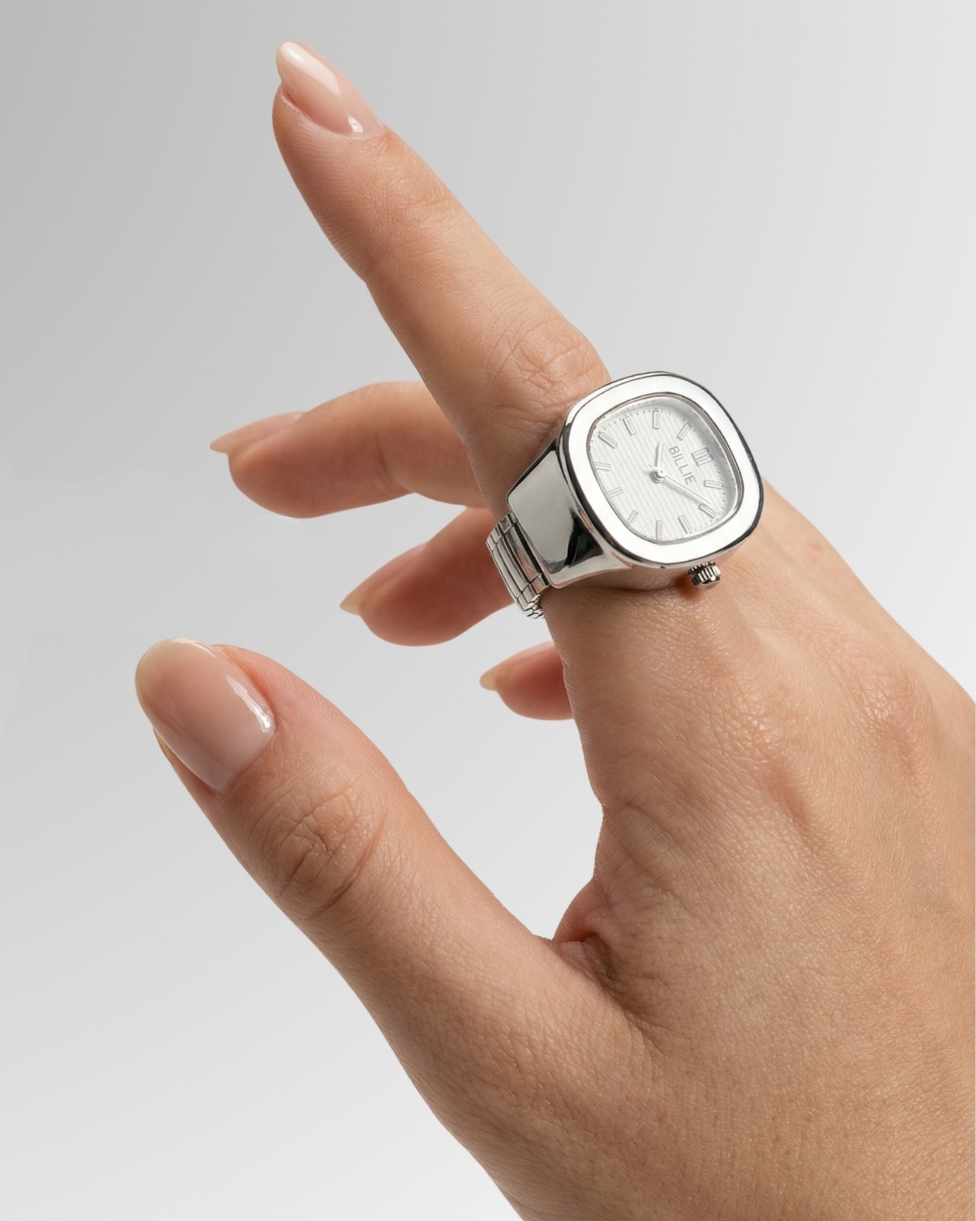 Hand with a silver watch, fingers slightly curled, on a gradient background.
