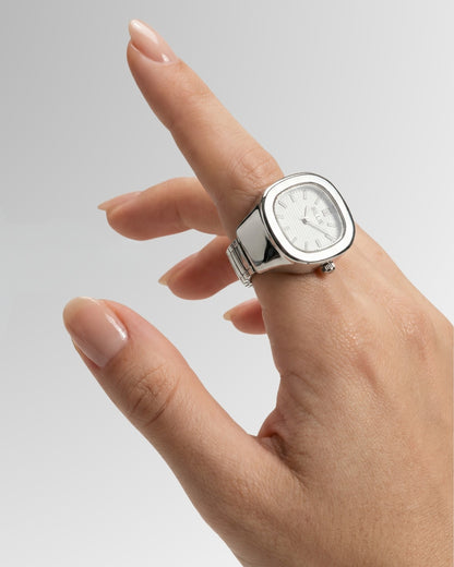 Hand with a silver watch, fingers slightly curled, on a gradient background.