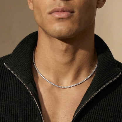 Man wearing a silver necklace against a neutral background