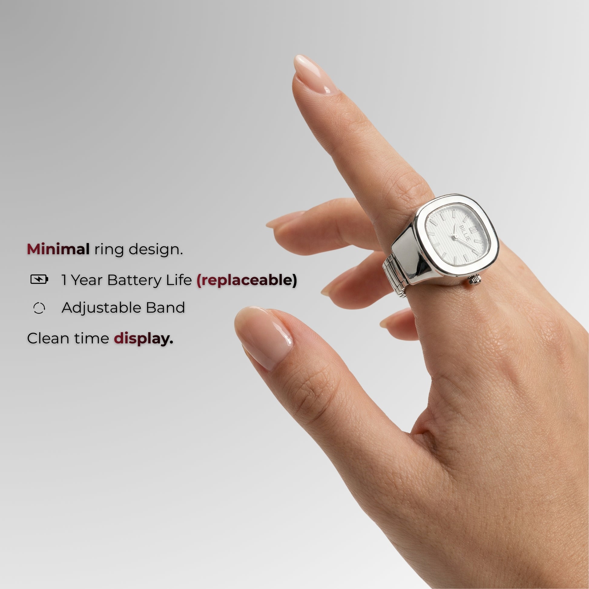 Hand wearing a ring with a watch face on a gray background