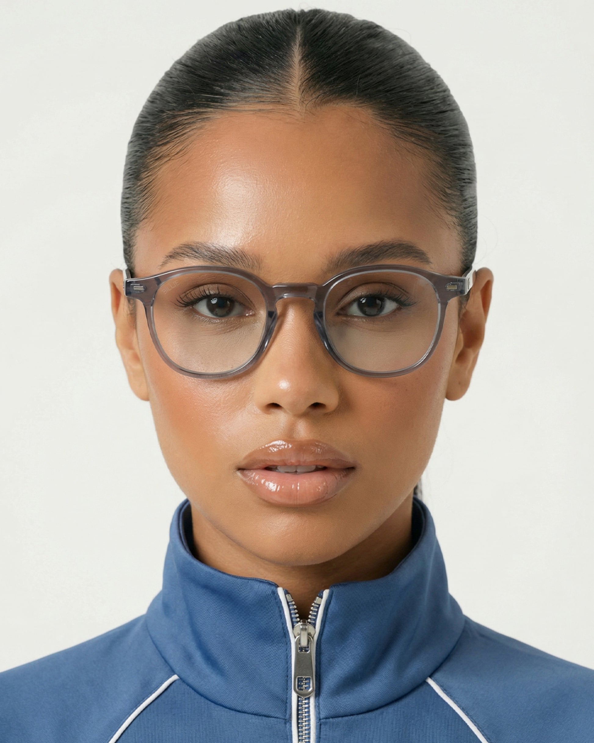 Close-up of a person wearing glasses and a blue zip-up jacket.