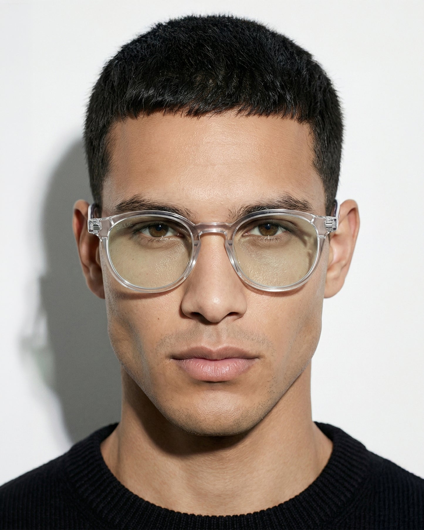 Close-up of a person wearing clear glasses with a neutral expression.