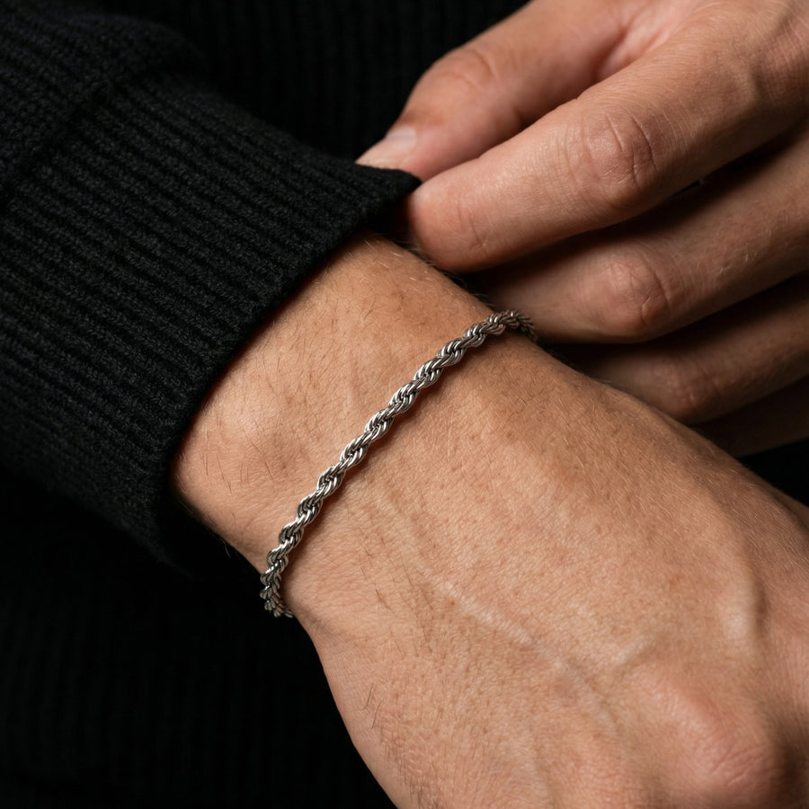Close-up of a hand wearing a silver bracelet on a dark background