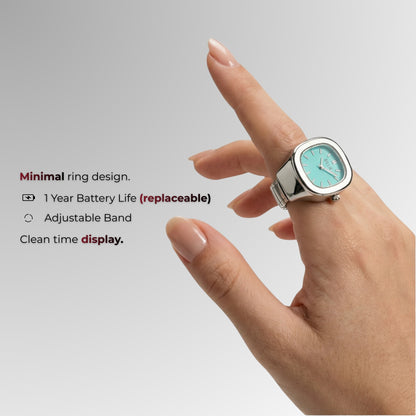 Ring with digital display worn on a finger against a light gray background