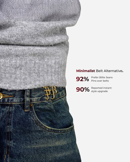 Close-up of a gray sweater and denim with a gold pin at the waist.