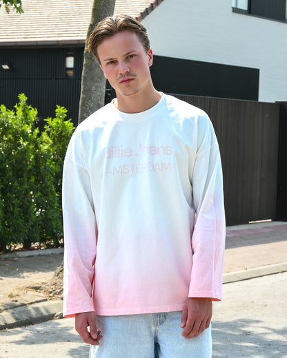 Person wearing a long-sleeve shirt with a gradient from white to pink and light blue jeans.