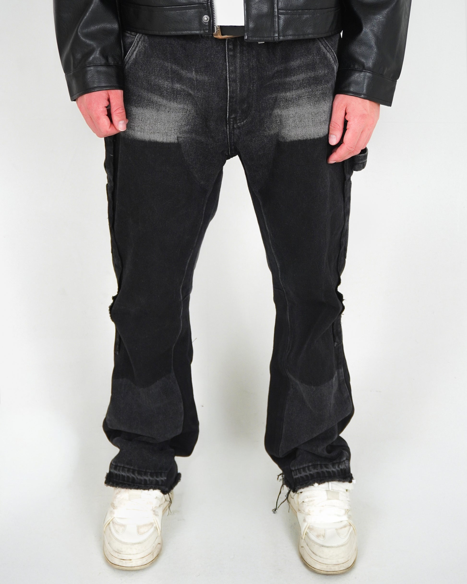Person wearing black pants and white sneakers, standing against a plain background.
