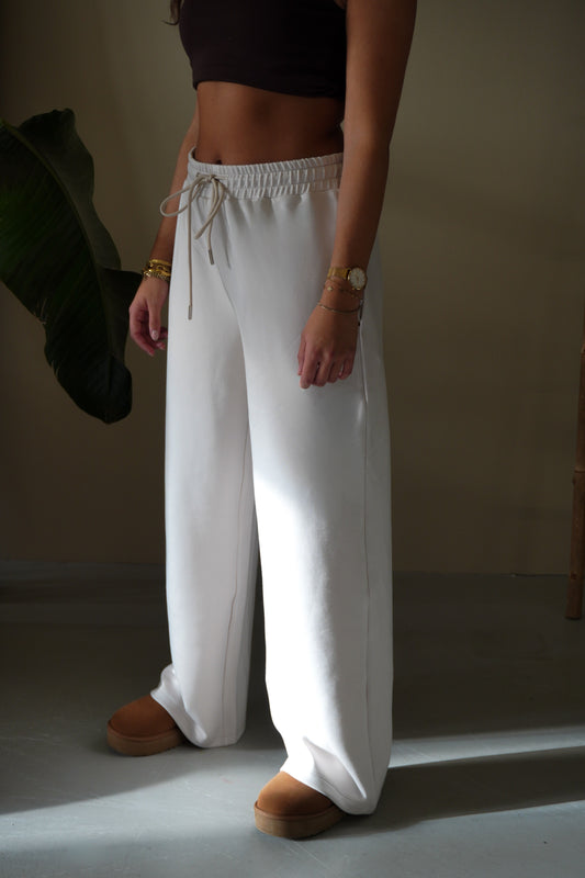 Person wearing white pants and a dark top in a minimal setting