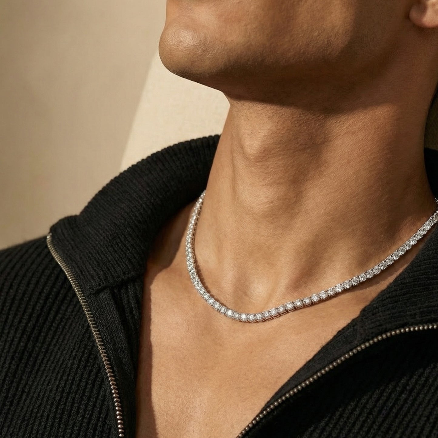 Close-up of a person wearing a diamond necklace against a neutral background