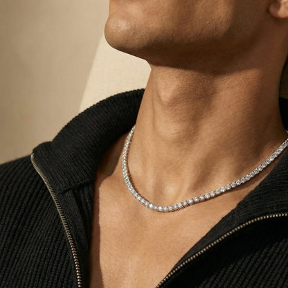 Close-up of a person wearing a diamond necklace against a neutral background