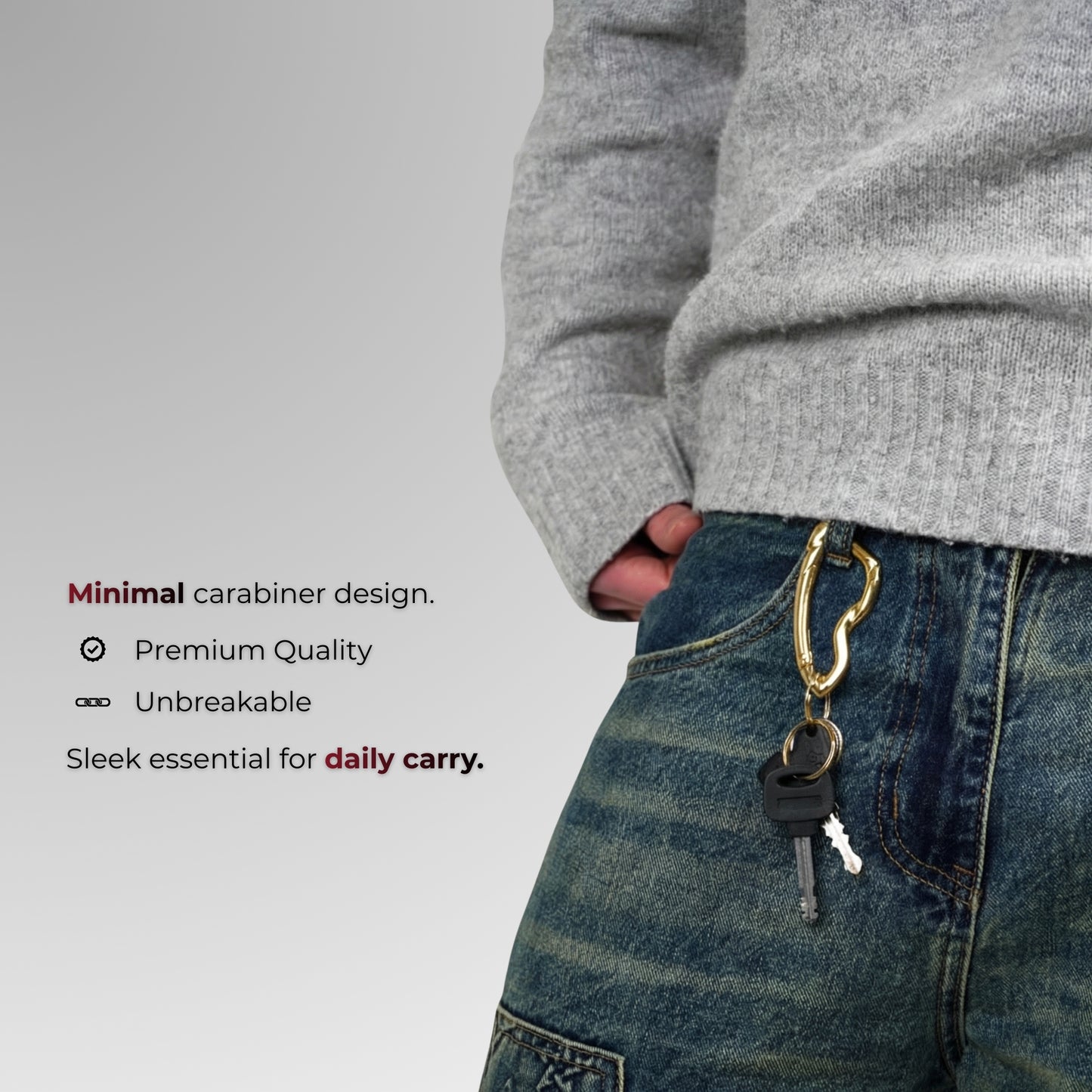 Person wearing a gray sweater and blue jeans with a carabiner attached, on a light gray background.