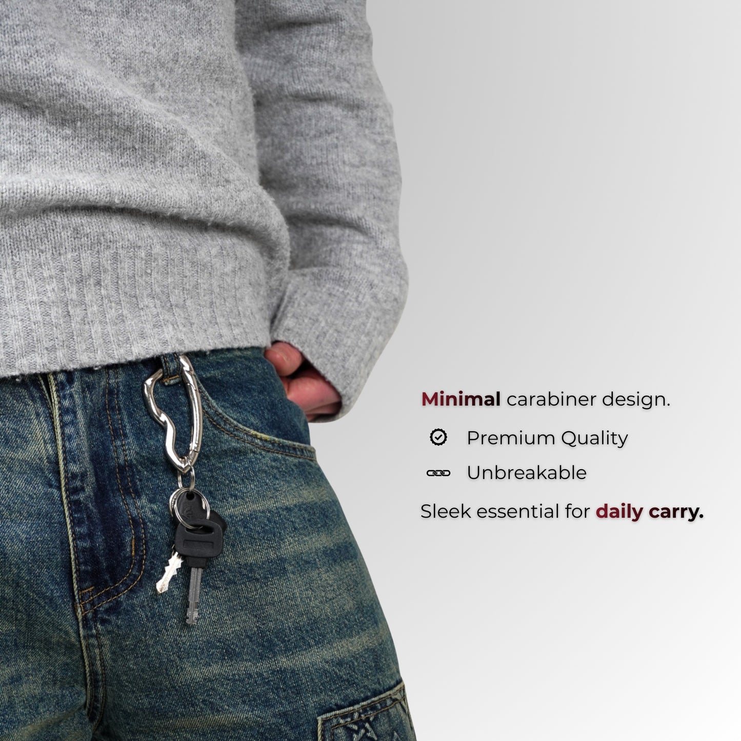 Persoon met een grijze trui en blauwe spijkerbroek met een sleutelhanger, op een lichtgrijze achtergrond.