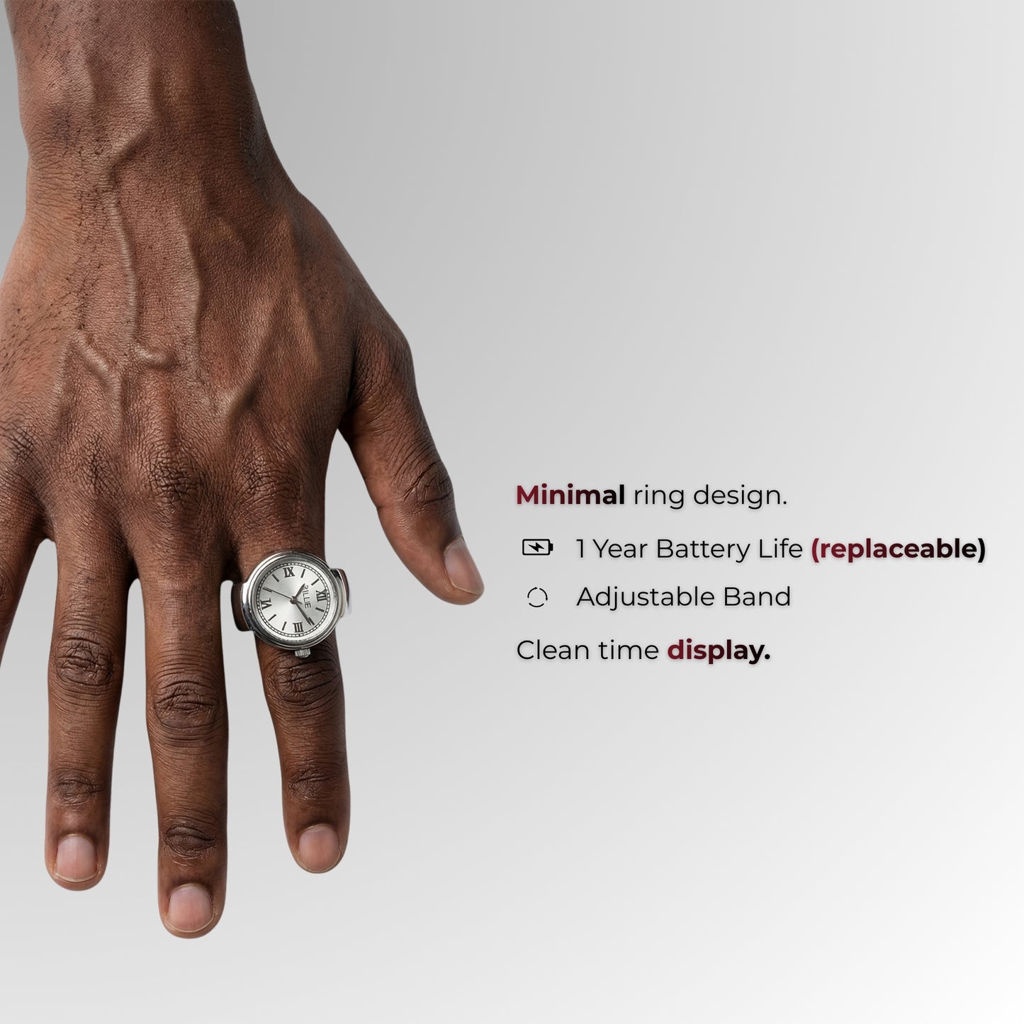 Hand met een ring met horloge-ontwerp op een grijze achtergrond