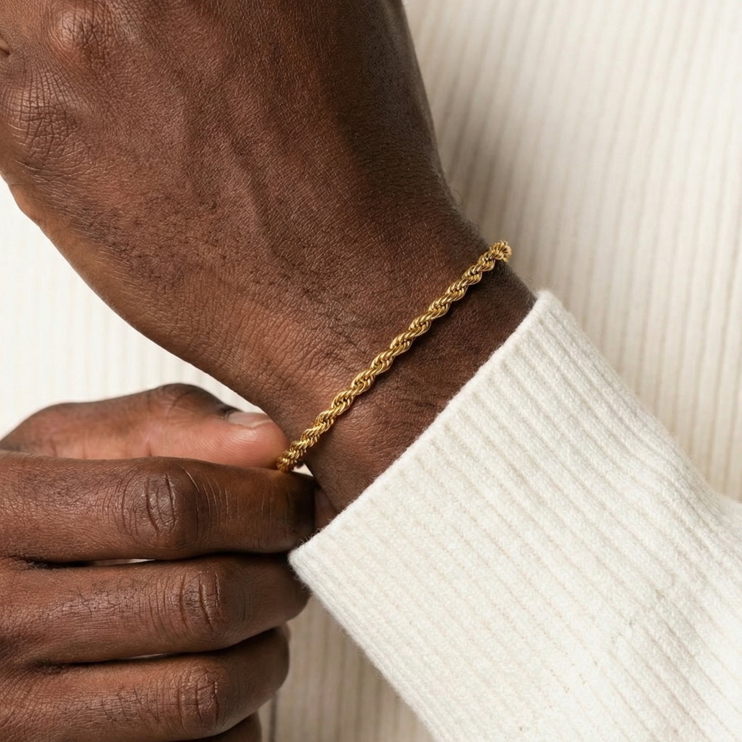 Gold bracelet on a wrist with a white sleeve