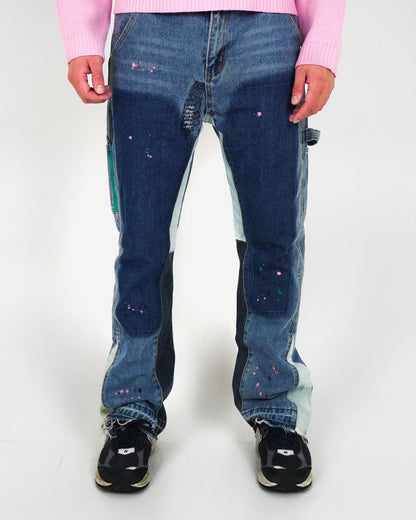 Person wearing distressed blue jeans with colorful paint splatters and black sneakers.