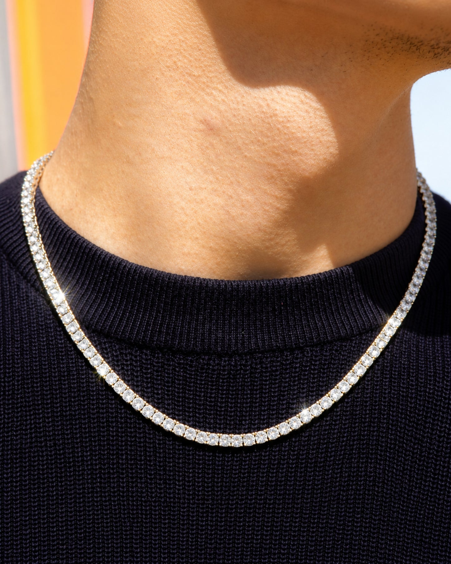 Close-up of a person's neck wearing a shiny necklace on a dark sweater.