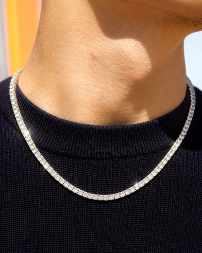 Close-up of a person's neck wearing a shiny necklace on a dark sweater.