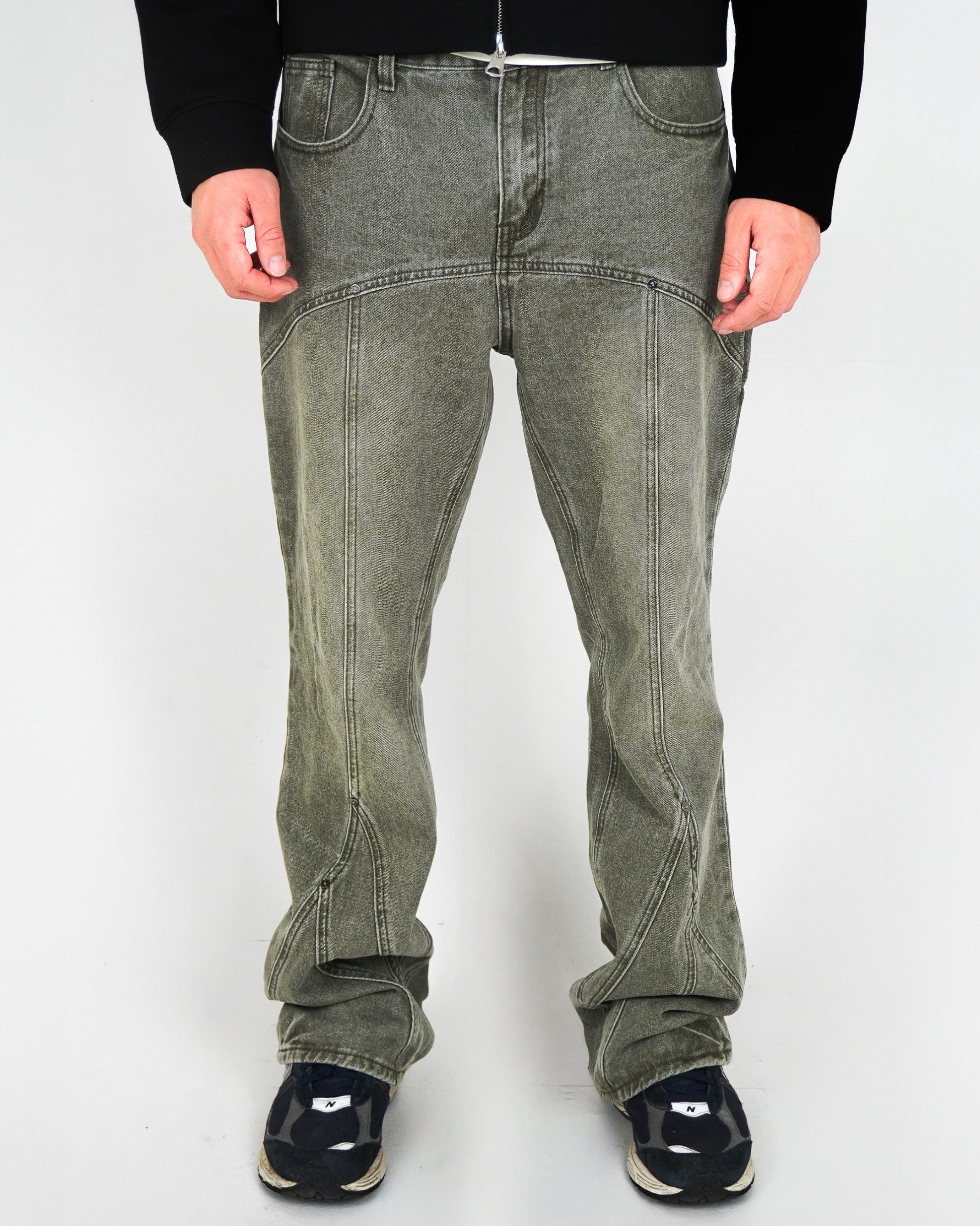 Person wearing green pants and black shoes, standing against a light background.