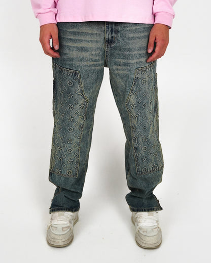 Person wearing embroidered denim pants and white sneakers, standing on a plain background.