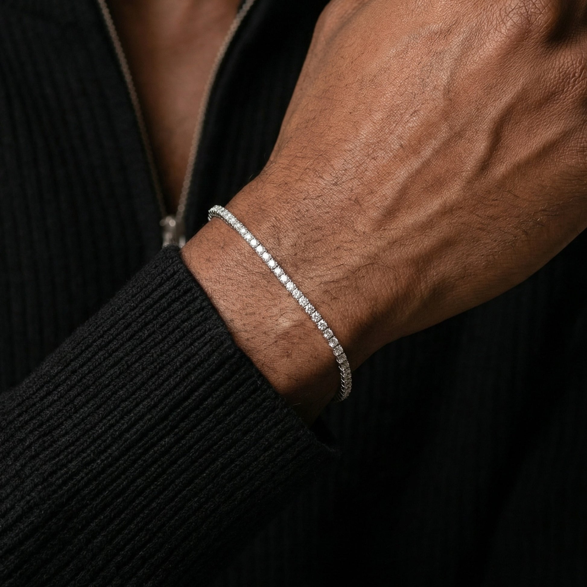 Close-up of a person's wrist wearing a silver bracelet against a dark background