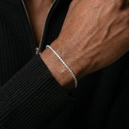 Close-up of a person's wrist wearing a silver bracelet against a dark background