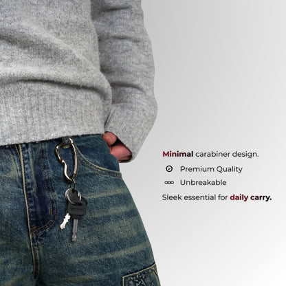 Person wearing a gray sweater and blue jeans with a keychain, on a light gray background.