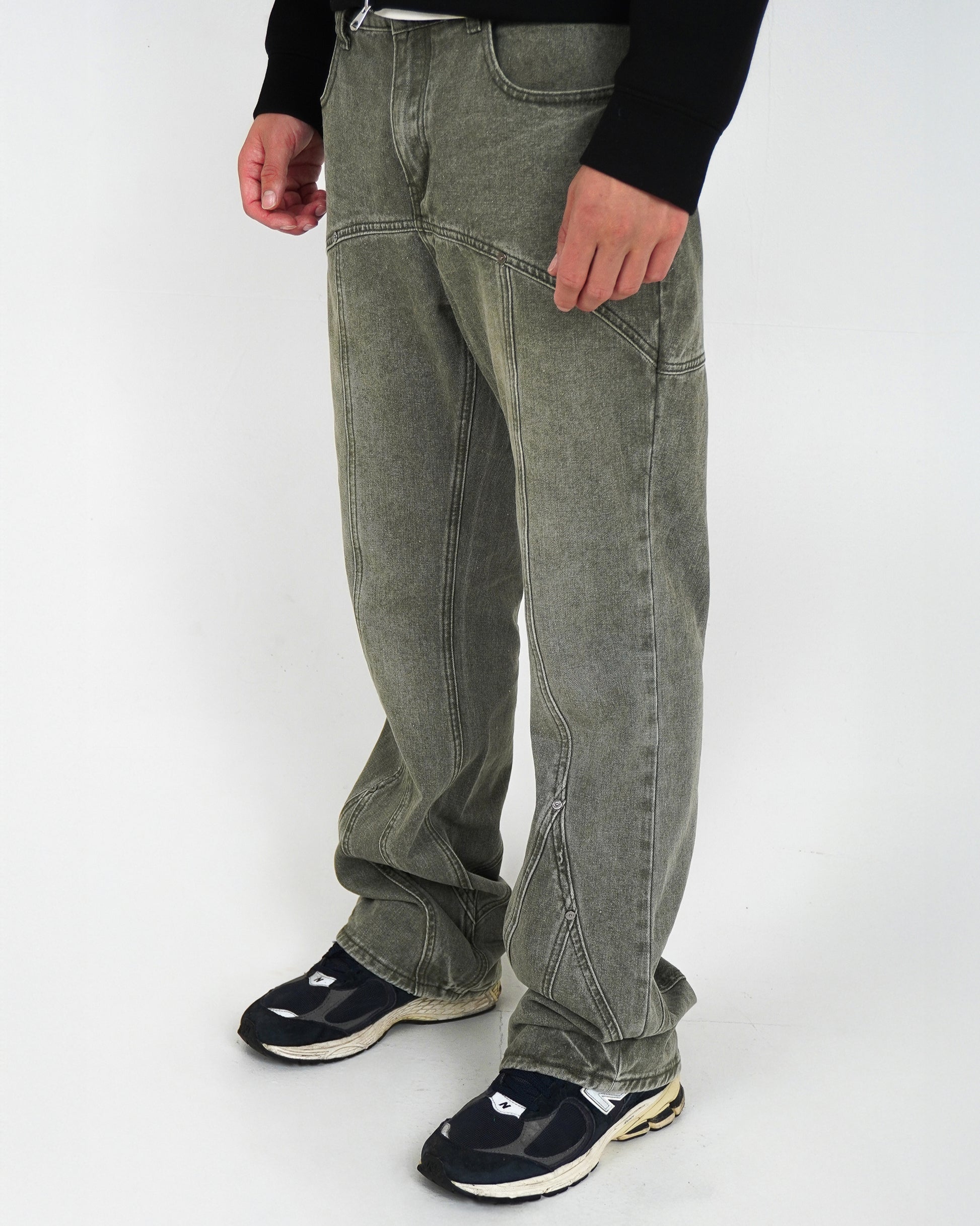 Person wearing light gray pants and black sneakers, standing on a plain background.