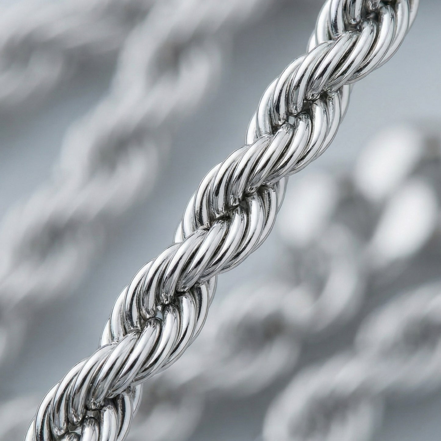 Close-up of a silver braided chain against a blurred metallic background