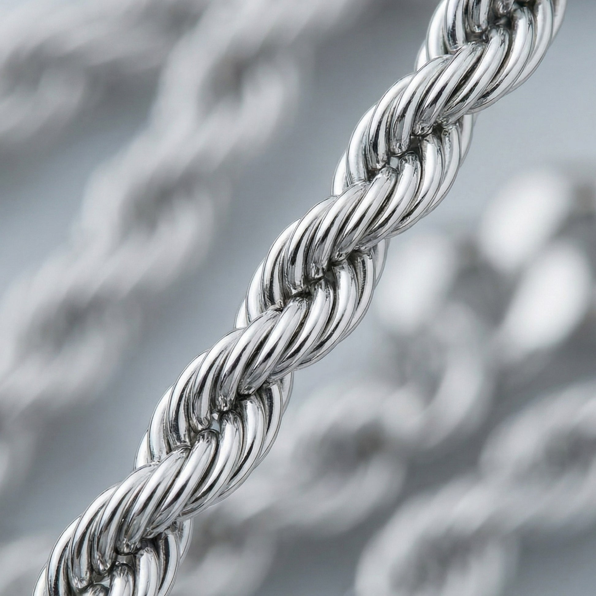 Close-up of a silver braided chain against a blurred metallic background