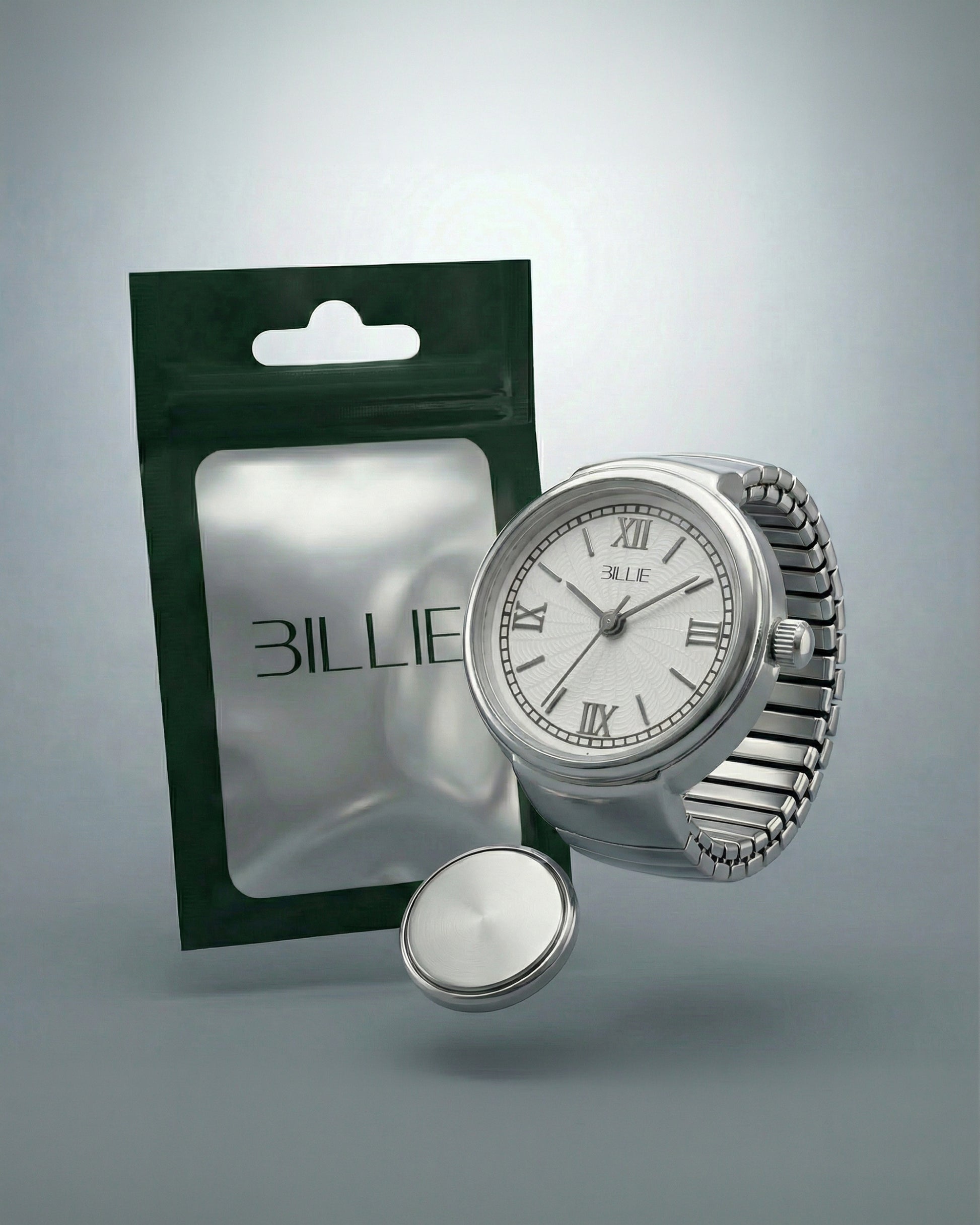 Silver watch with Roman numerals next to a green and silver packaging and a round silver object.