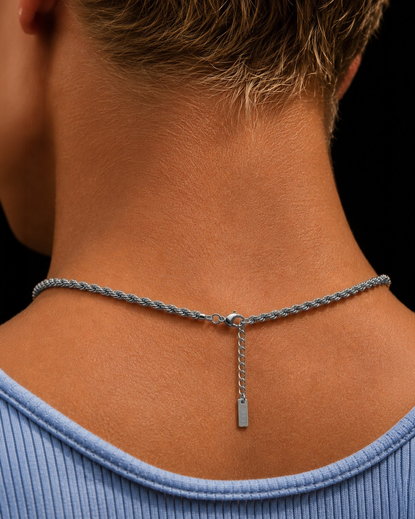 Close-up of a braided silver chain necklace on the back of a neck.