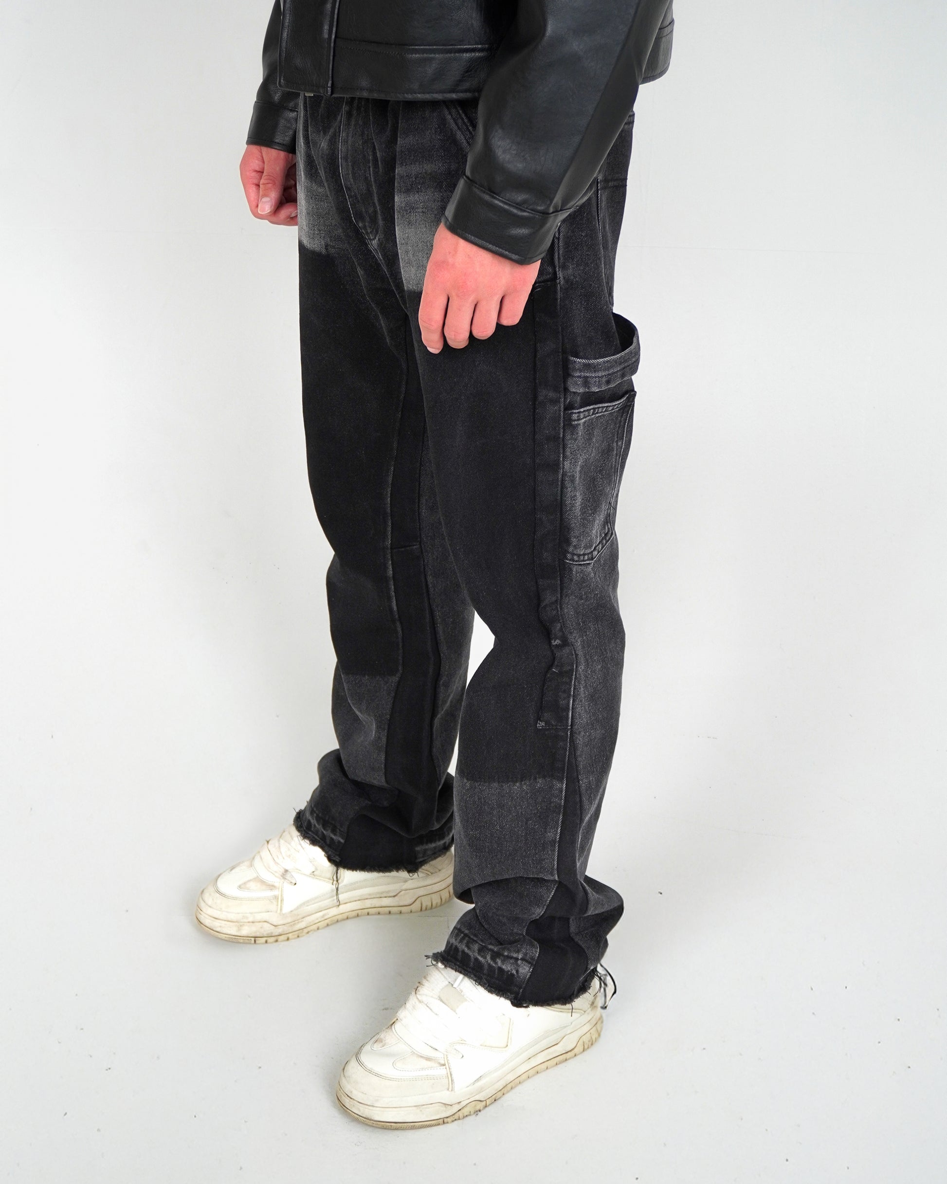 Person wearing black pants and white sneakers, standing on a light background.