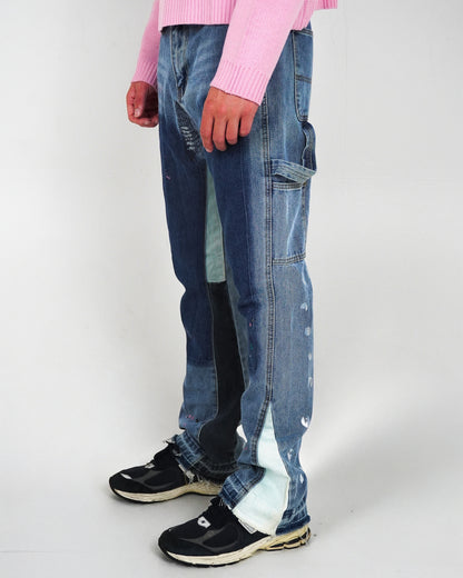 Person wearing blue jeans with a mix of denim shades and black sneakers, standing against a plain background.