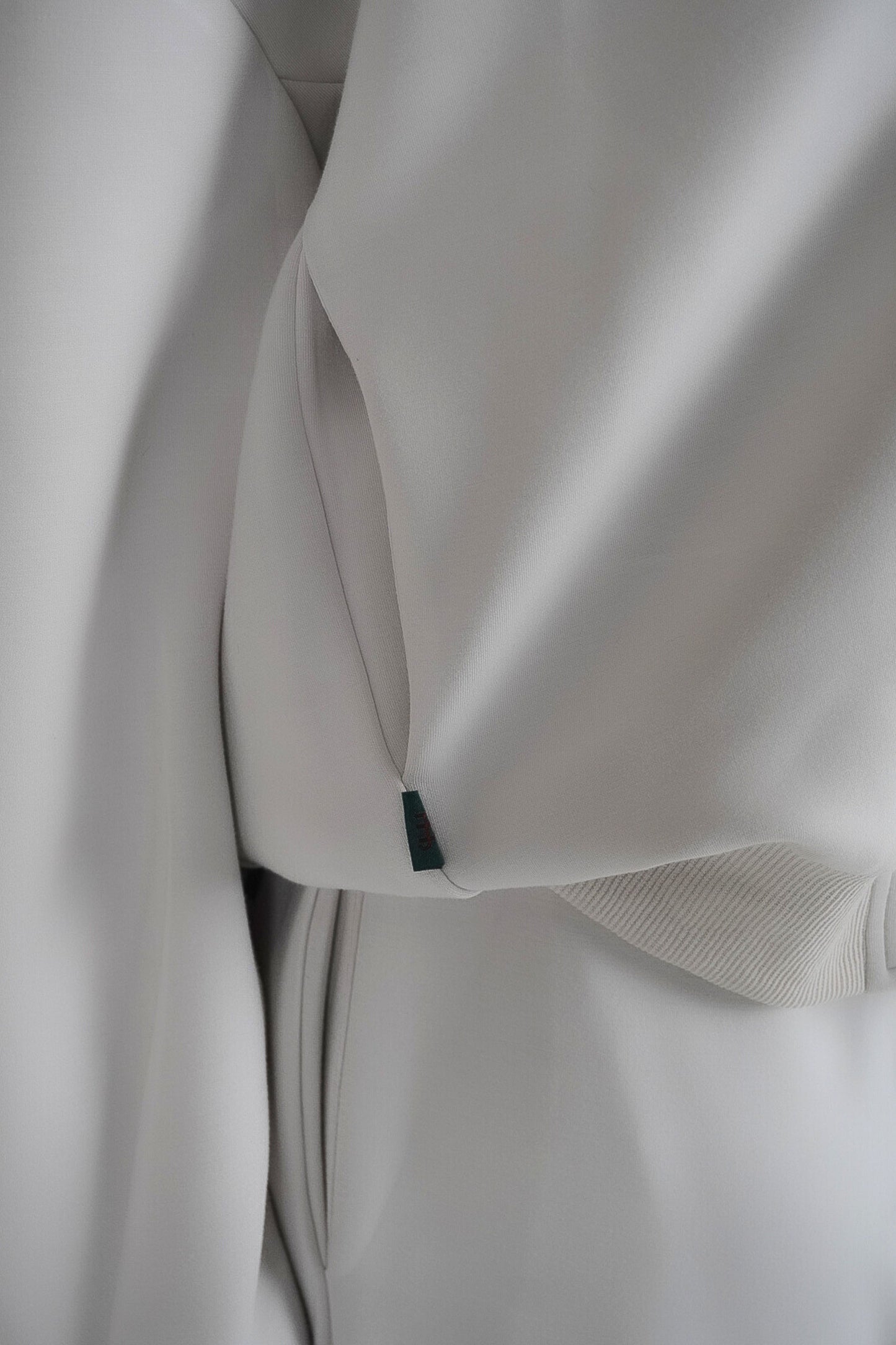 Close-up of a light gray fabric with a small green tag.